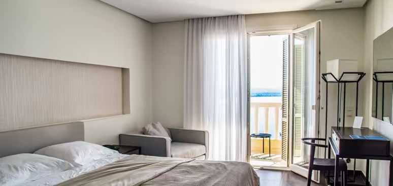 Hotel room with an open balcony door overlooking the sea