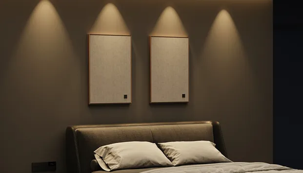 Hotel bed with two fabric art panels on the wall lit by warm spotlights