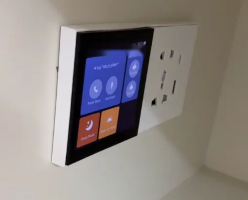 The 4-inch voice panel installed on the guest room wall next to a power socket